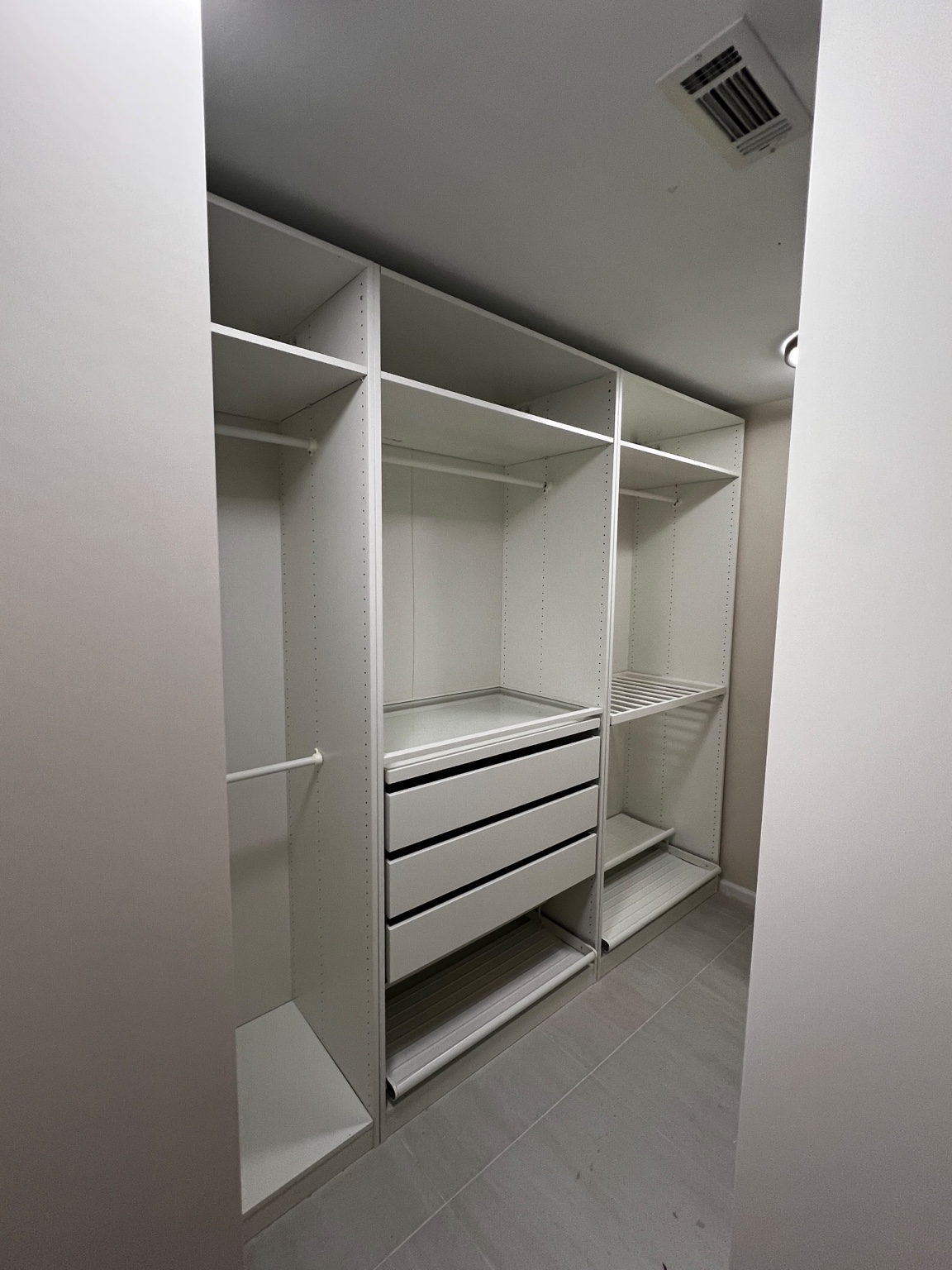 Side view of the same white closet showing hanging rods, shelves and drawers.