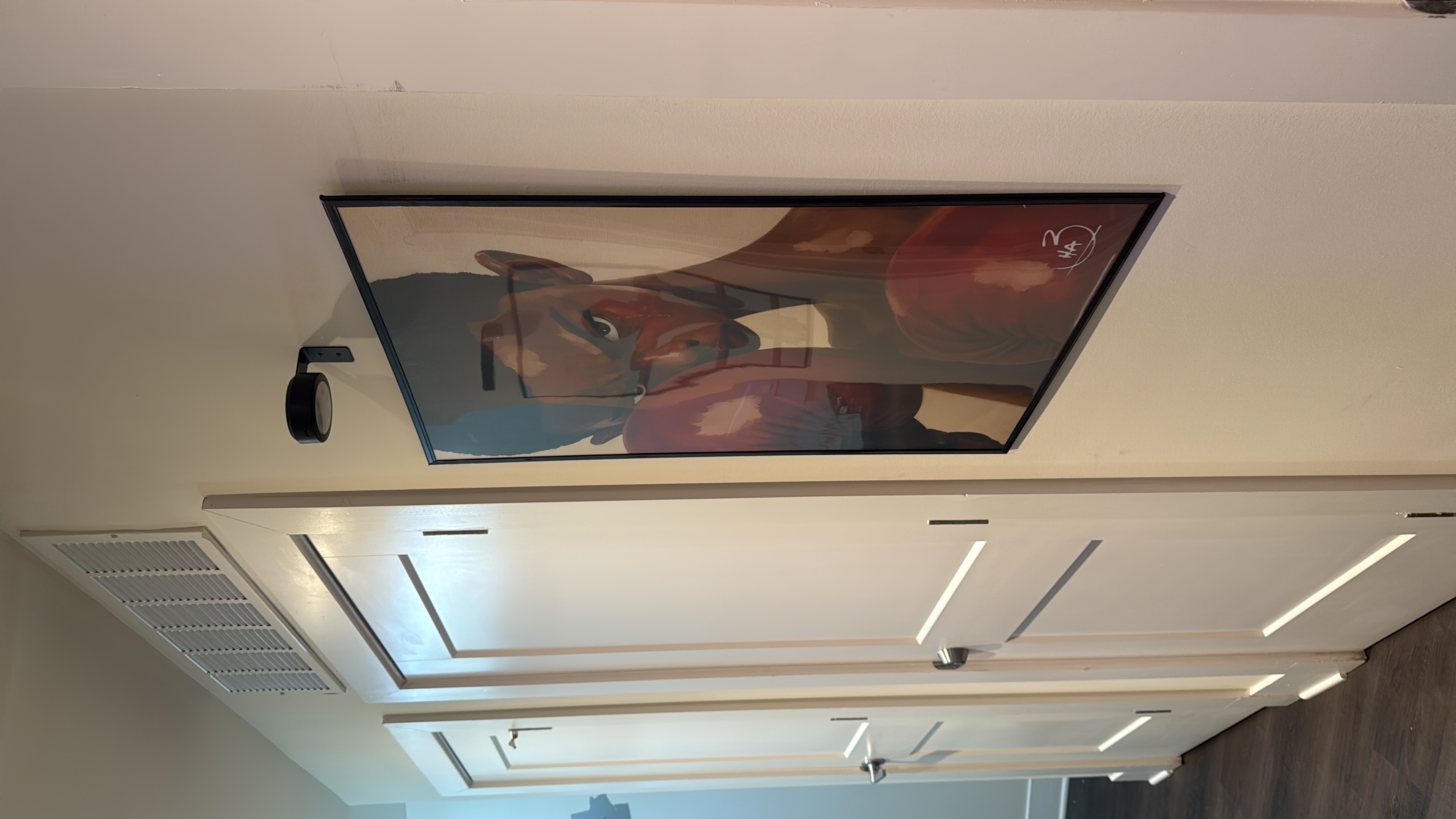 Framed boxing artwork with a small light mounted above it.