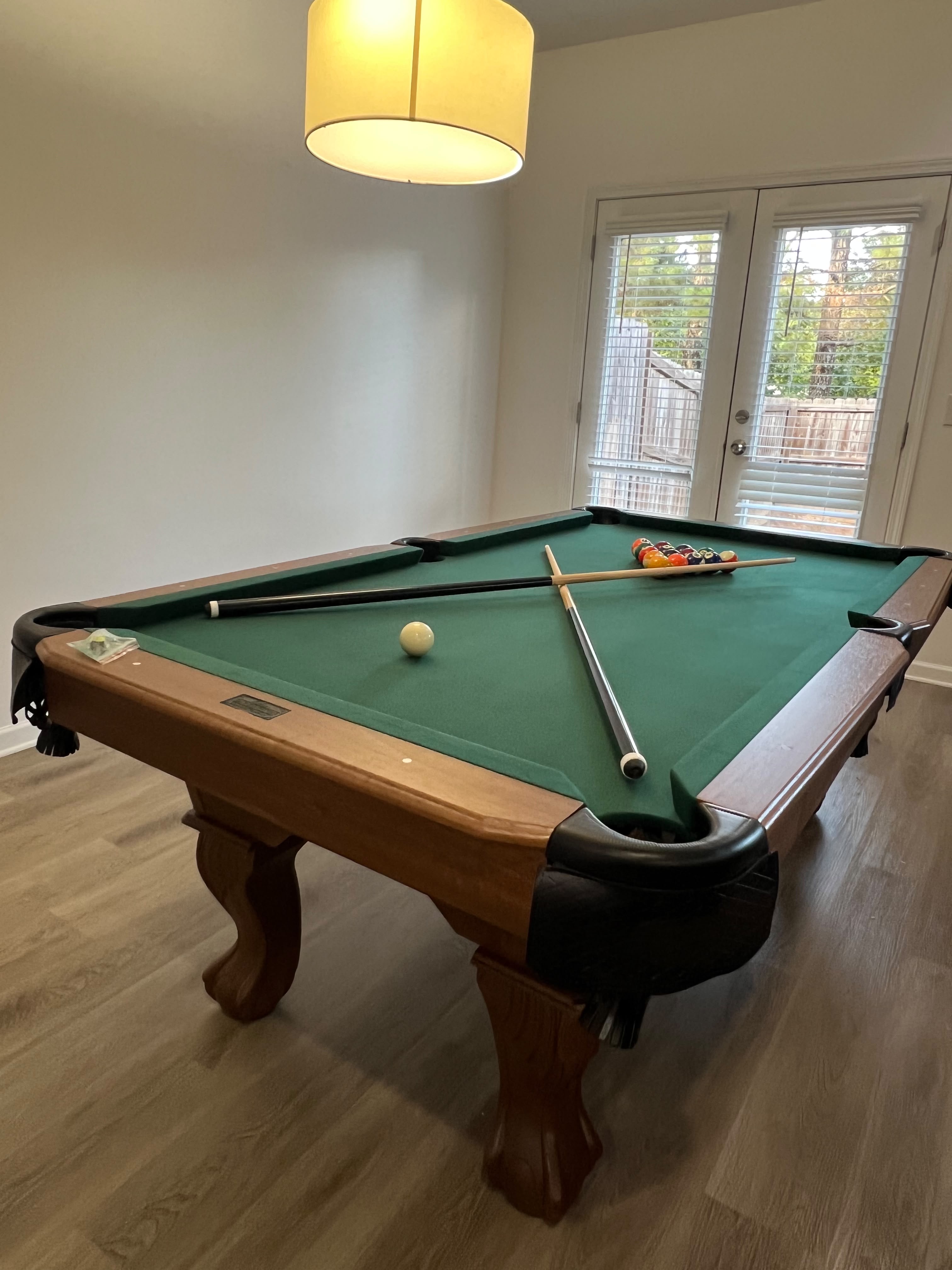 Wood pool table with green felt in a residential game room.