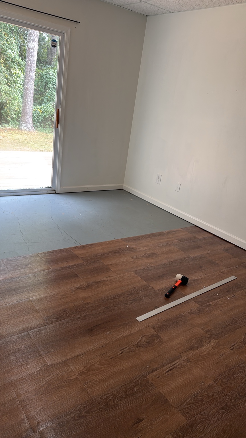 Partially installed wood-look vinyl flooring with the remaining subfloor and tools visible.