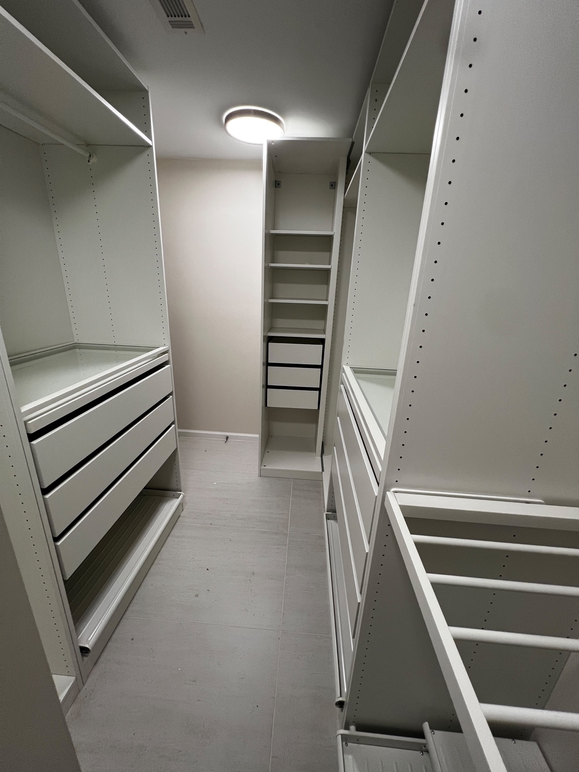 White modular walk-in closet with shelving, drawers and pull-out racks.