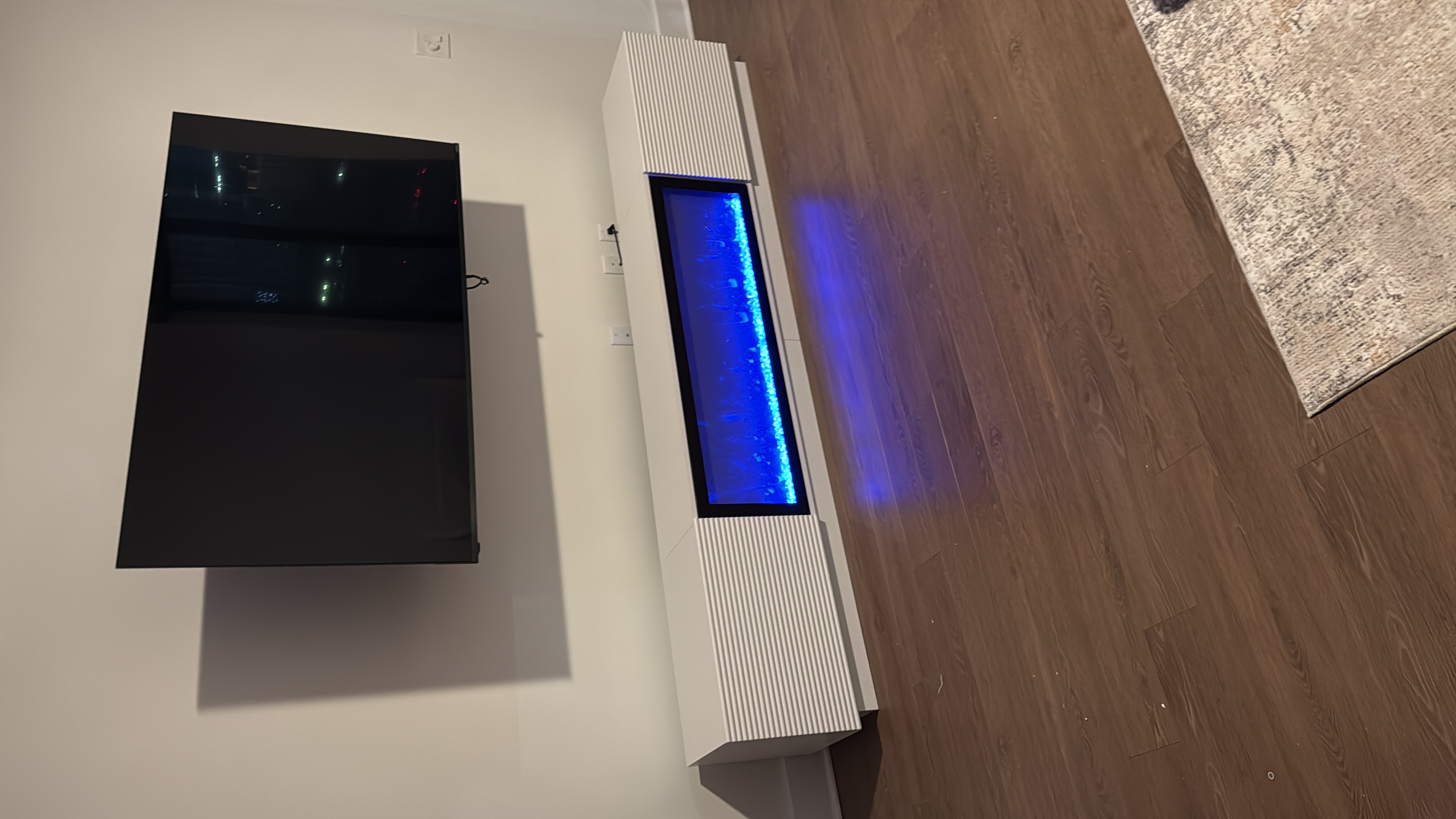Wall-mounted television above a white media console with an electric fireplace.